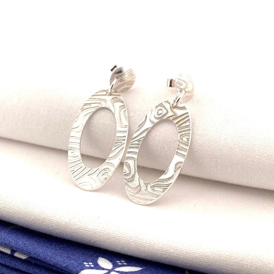 Engraved Oval sterling silver drop earrings on folded cream fabric