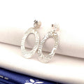 Engraved Oval sterling silver drop earrings on folded cream fabric