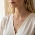 Blonde woman wearing gold vertical bar pendant close-up