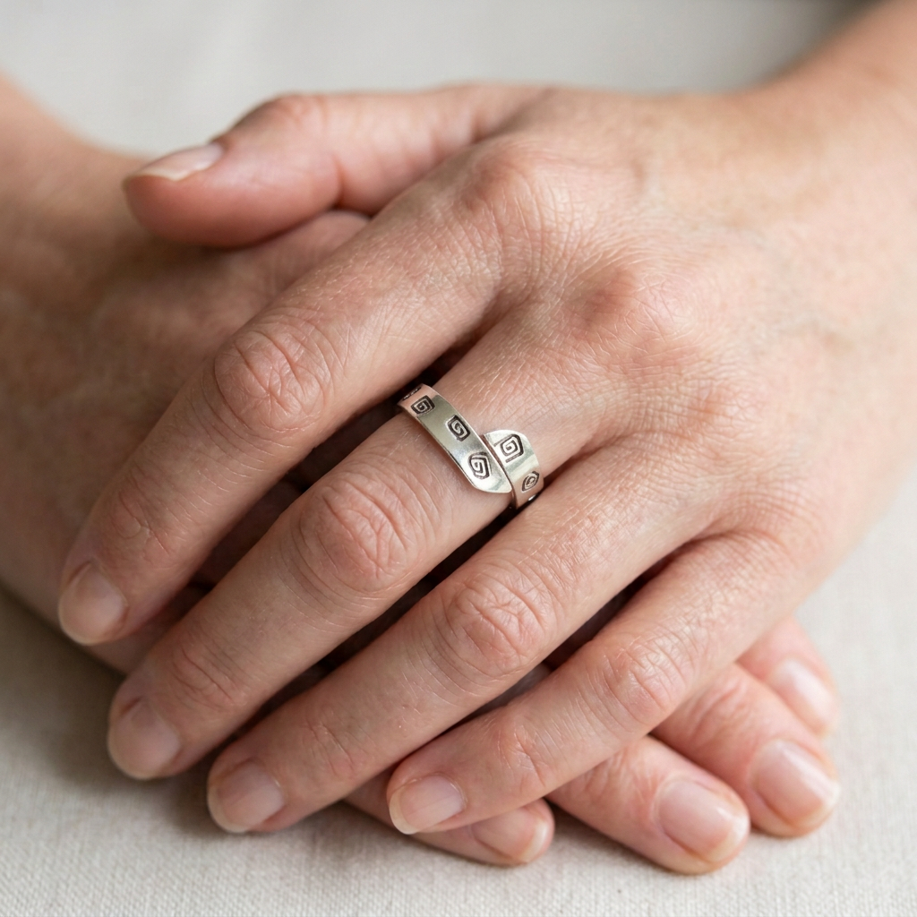 Brighter silver adjustable ring with defined Aztec detailing on clasped slender hands