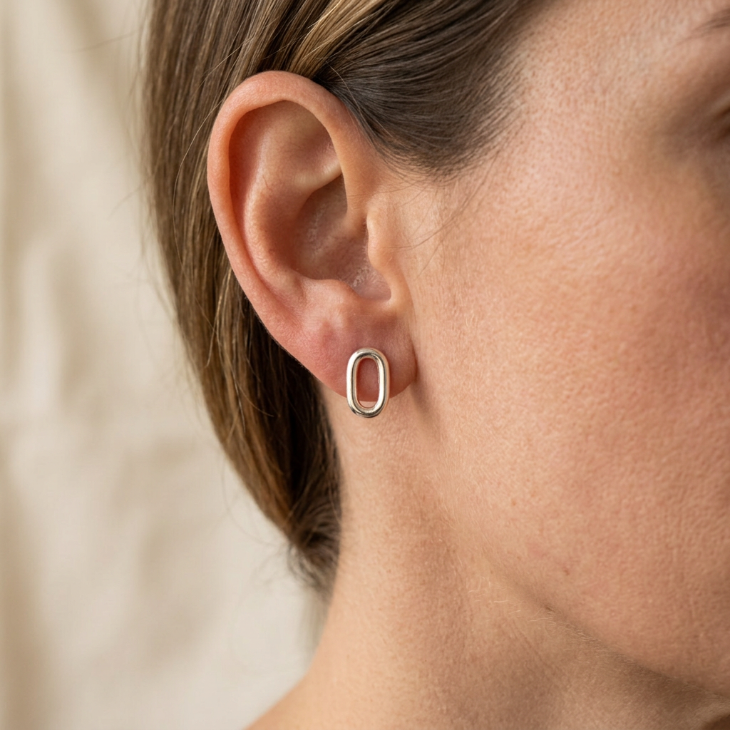 Close-up of a woman wearing the silver oval stud earring