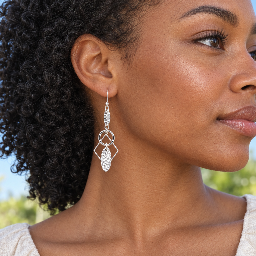 Model wearing Lyra sterling silver ear-hook earrings beside a window