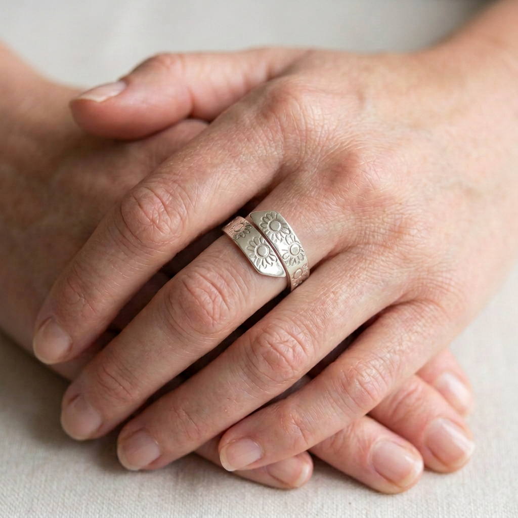 Embossed daisy adjustable silver band on clasped slender hands