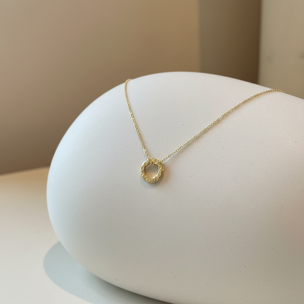 Gold hammered pendant draped on ceramic