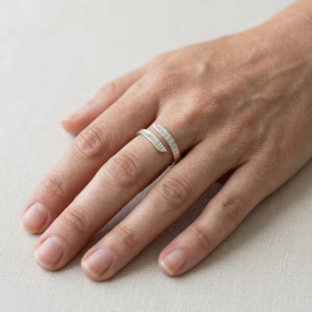Linear-textured adjustable silver ring on a slender hand