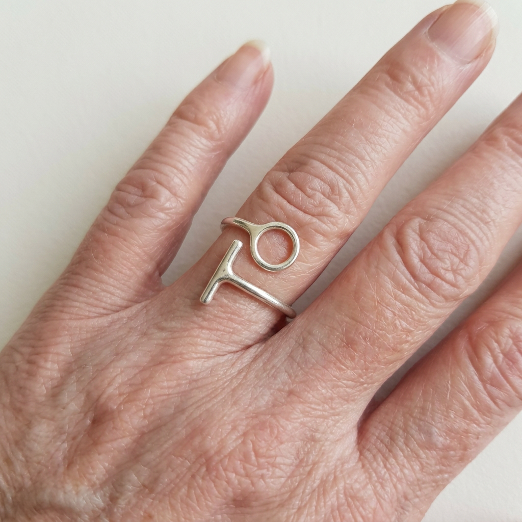 Open-circle and T-bar adjustable silver ring on long slender fingers