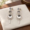 Pair of layered silver drop earrings on a dressing table