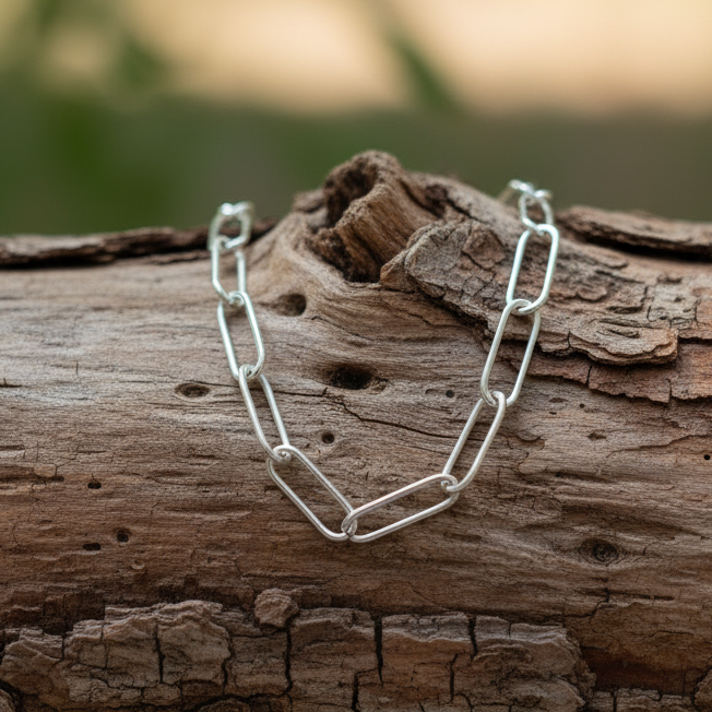 Paperclip chain bracelet draped over a log