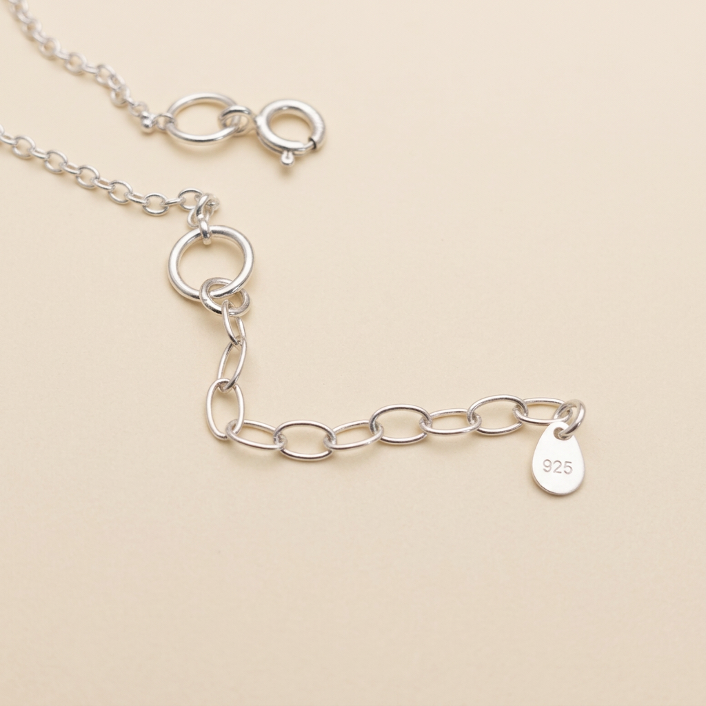 Silver necklace extension on a smooth ivory surface