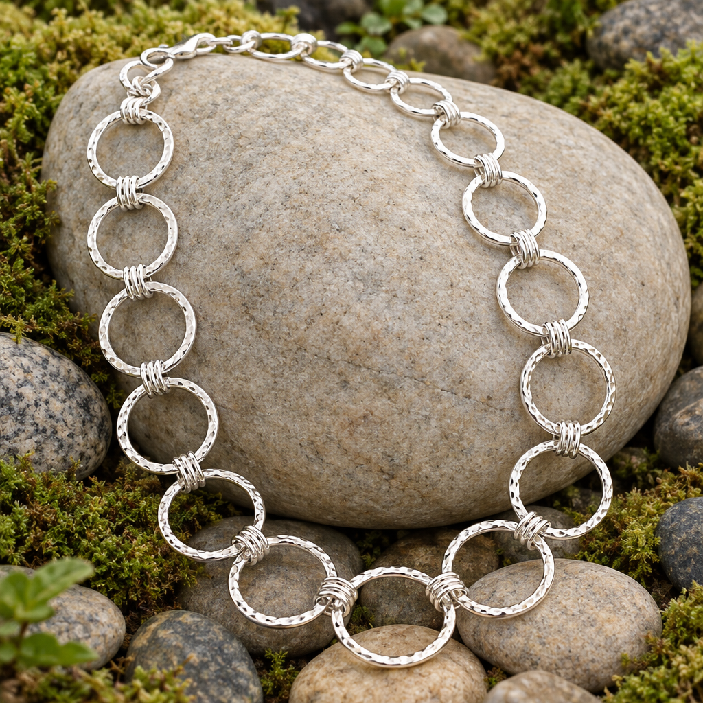 Silver ring necklace draped over a pebble outdoors