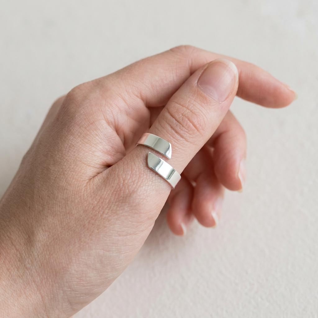 Smooth adjustable silver band on a young adult’s slender thumb