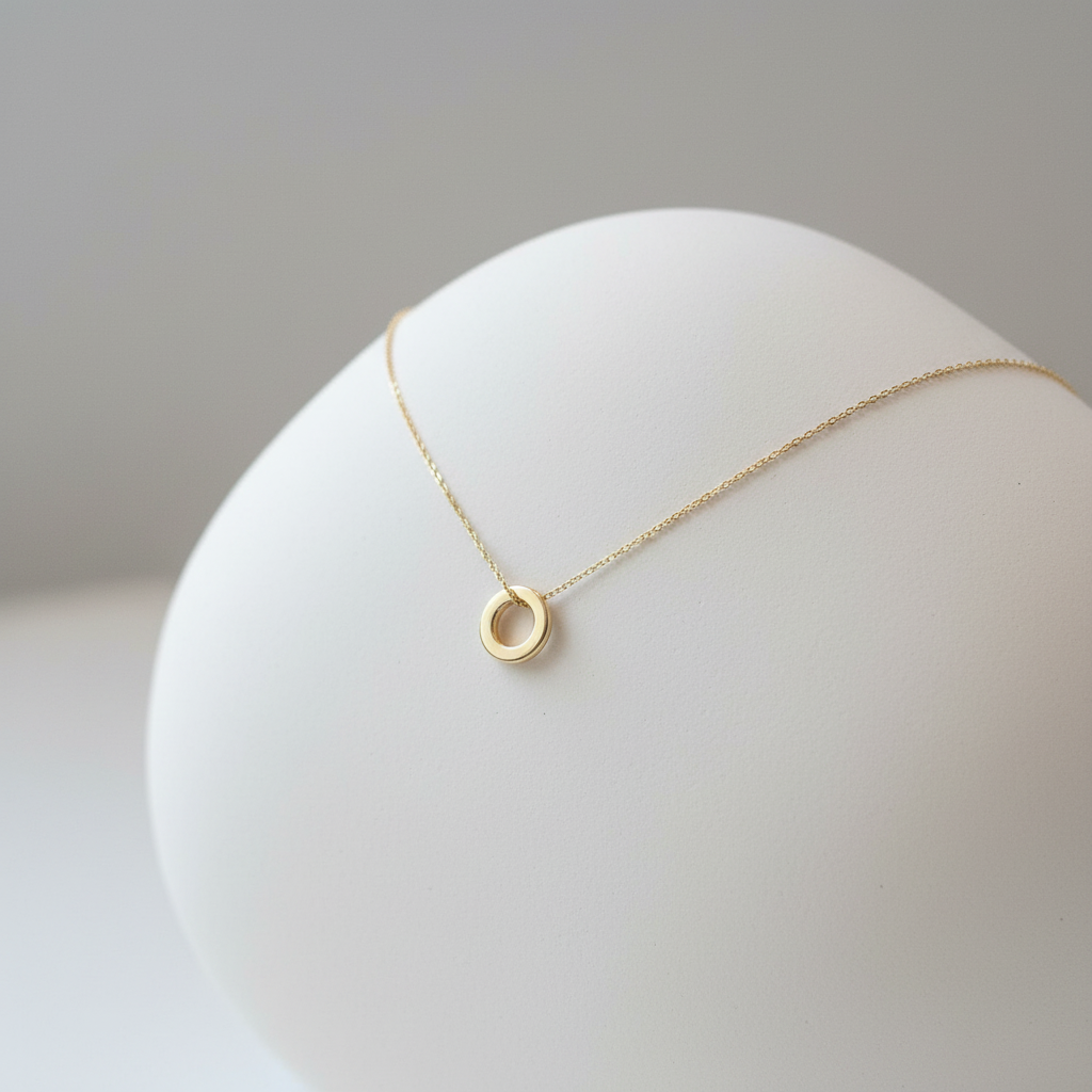 Smooth gold circle pendant draped over ceramic