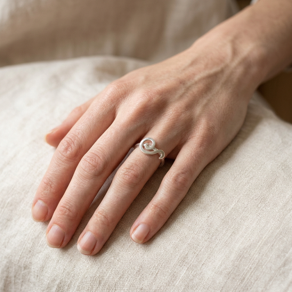 Spiral ring on a younger, slender hand resting on linen