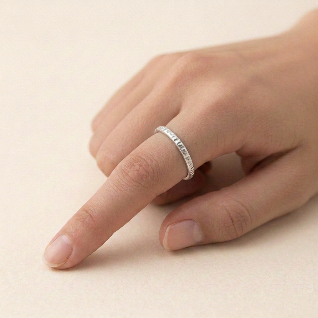 Thinner linear-textured silver ring on a slender hand