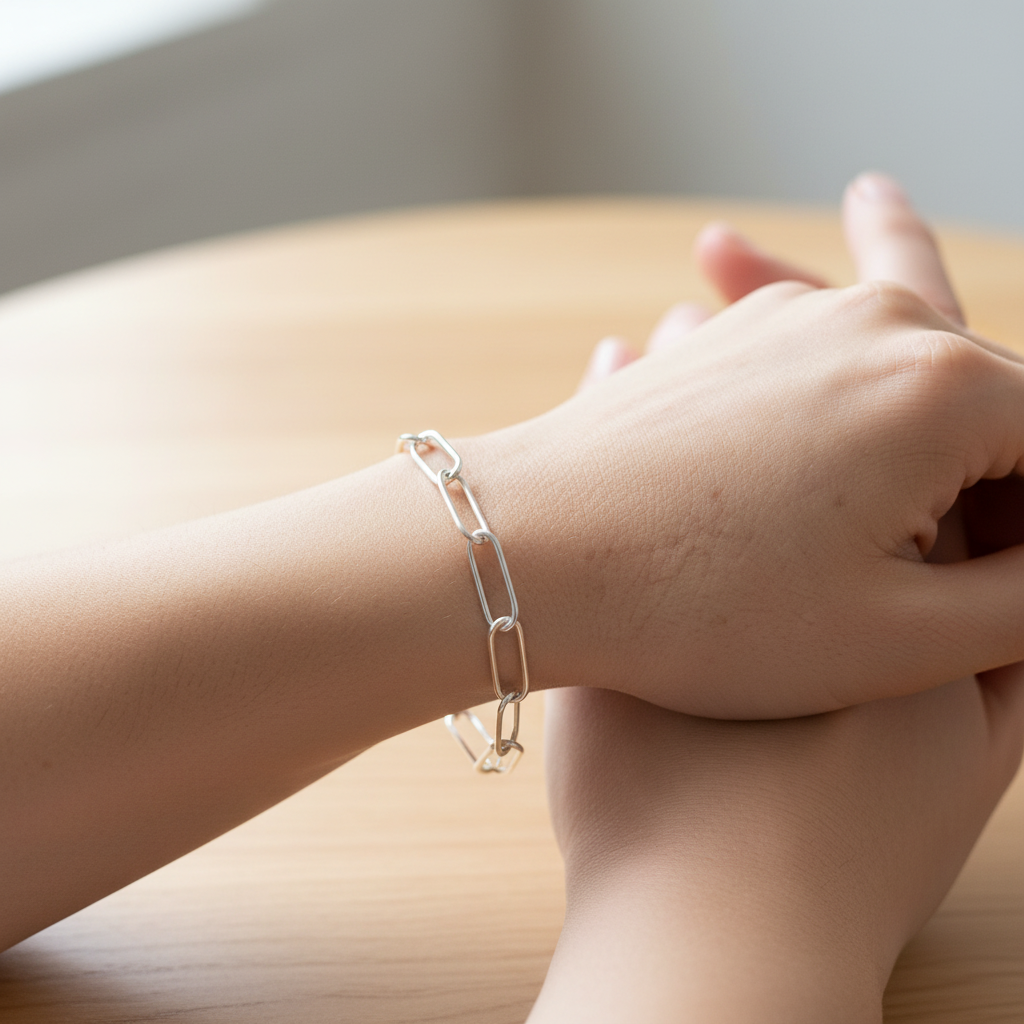 Young woman with folded hands wearing silver paperclip chain bracelet